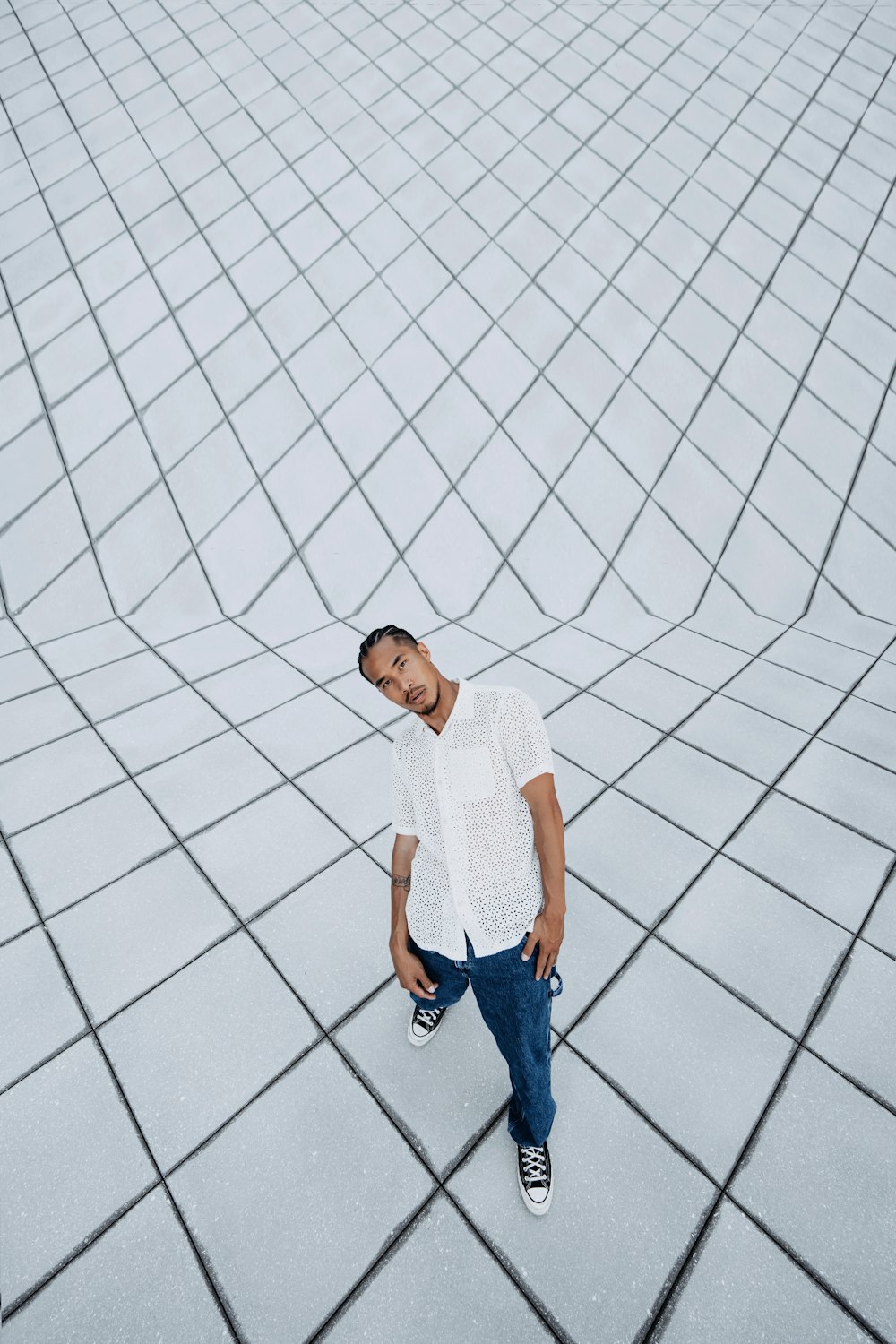 un uomo in piedi su un pavimento piastrellato con una camicia bianca