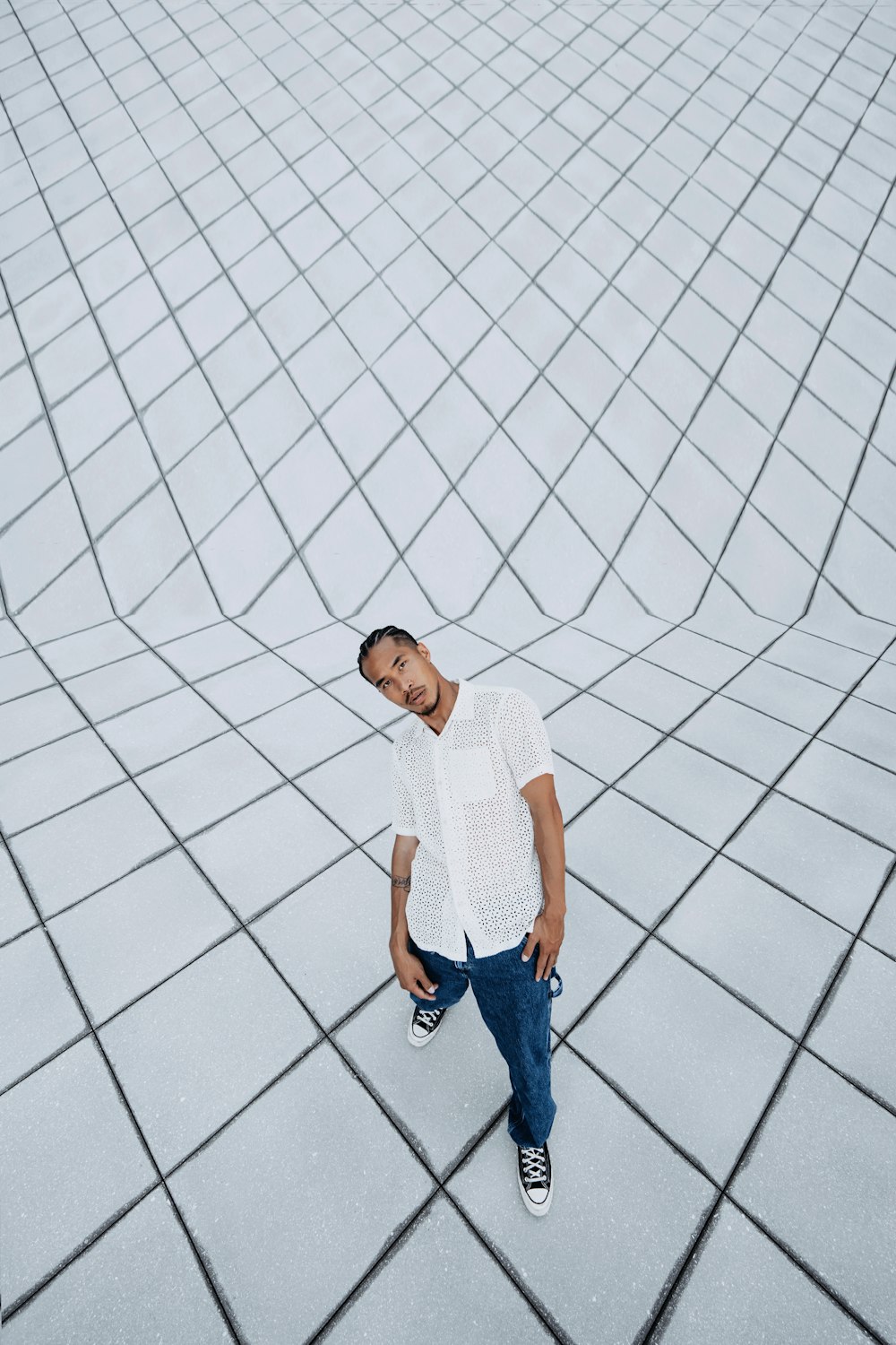 a man standing on a tiled floor in a white shirt