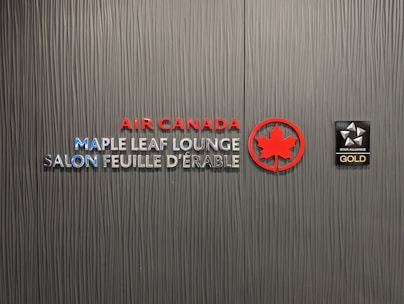 A textured wall featuring the logos and text for Air Canada Maple Leaf Lounge and Star Alliance Gold. The text includes bilingual English and French, with the Air Canada logo prominently displayed in red next to a stylized maple leaf.