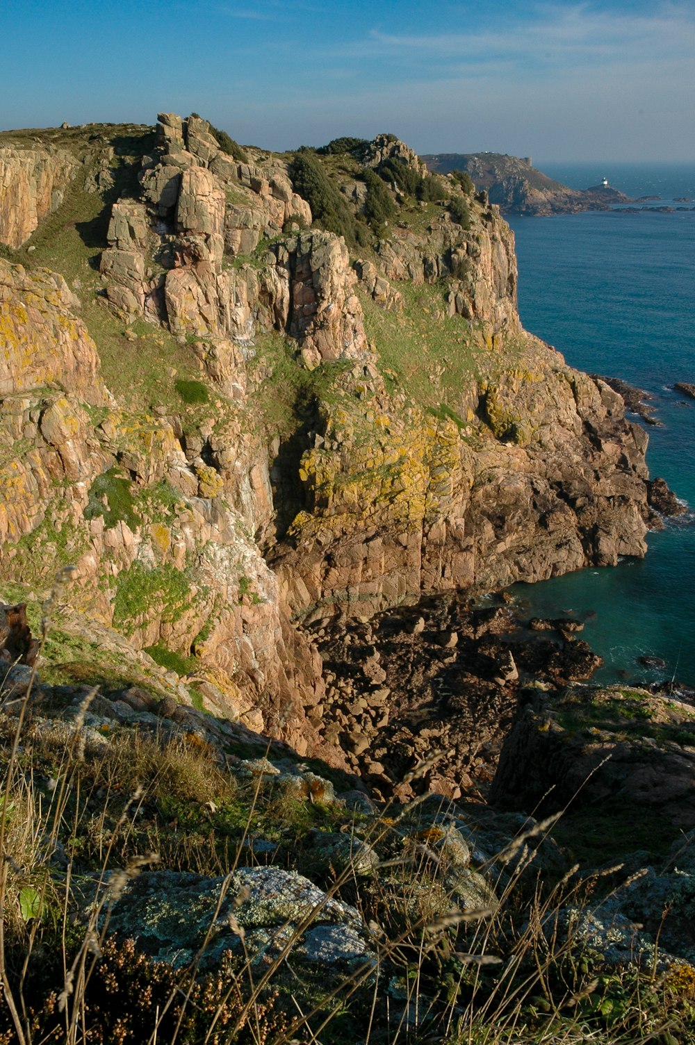 a rocky cliff overlooks the ocean on a sunny day