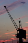 Close-up of d'liebeld's precise crane operation lifting steel beams with golden sunset light.