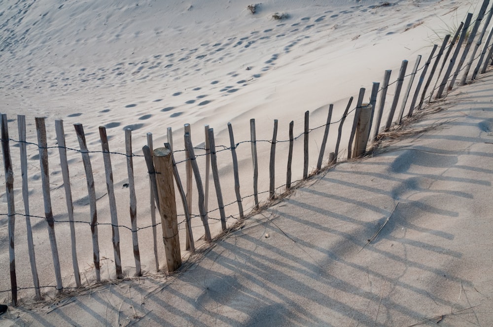 a wooden fence with a sand dune in the background