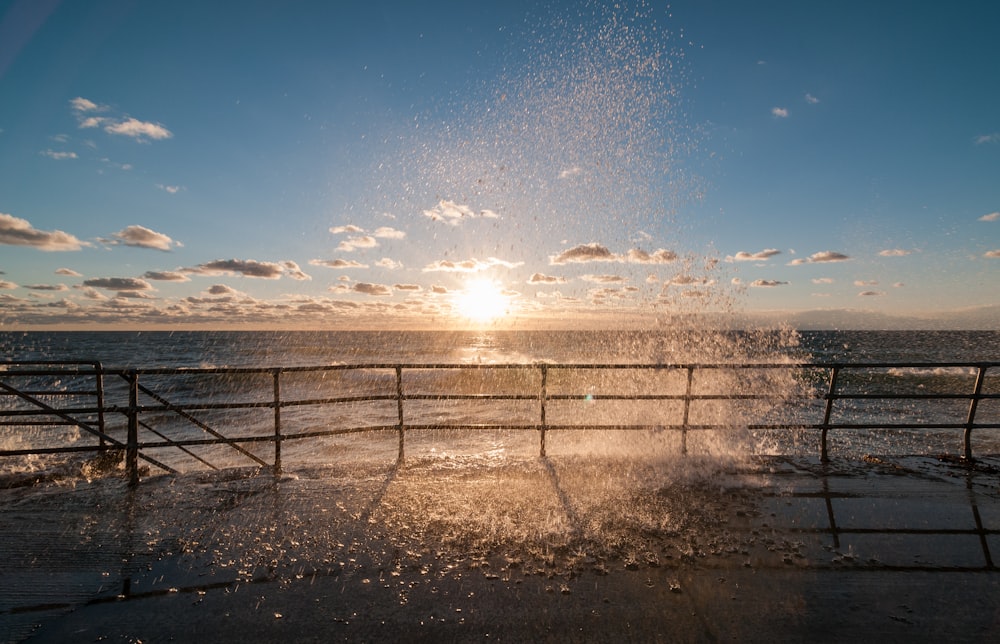 the sun is setting over the ocean and the water is splashing