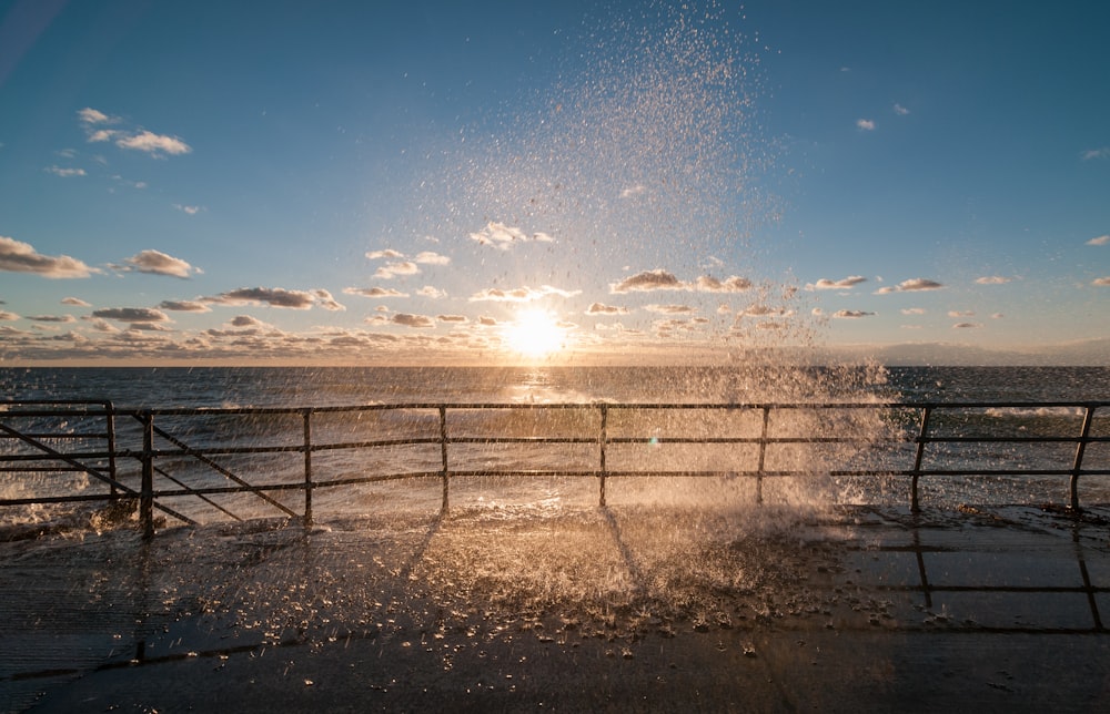 El sol se está poniendo sobre el océano y el agua está salpicando