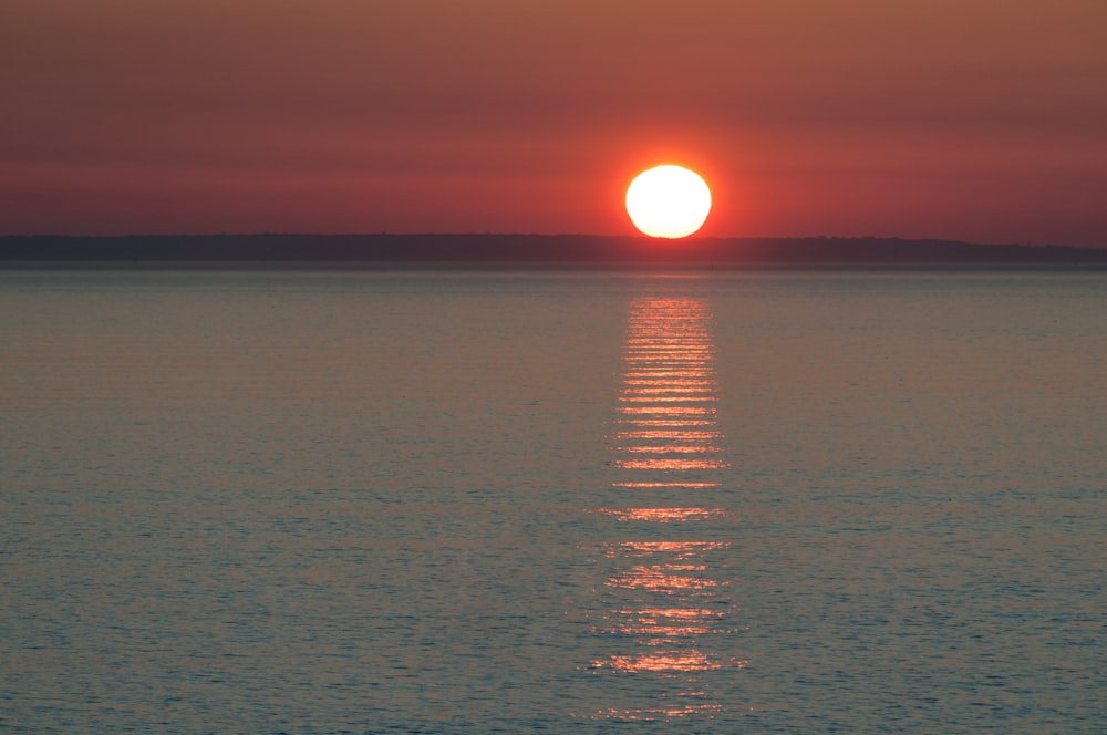 a large body of water with a sunset in the background