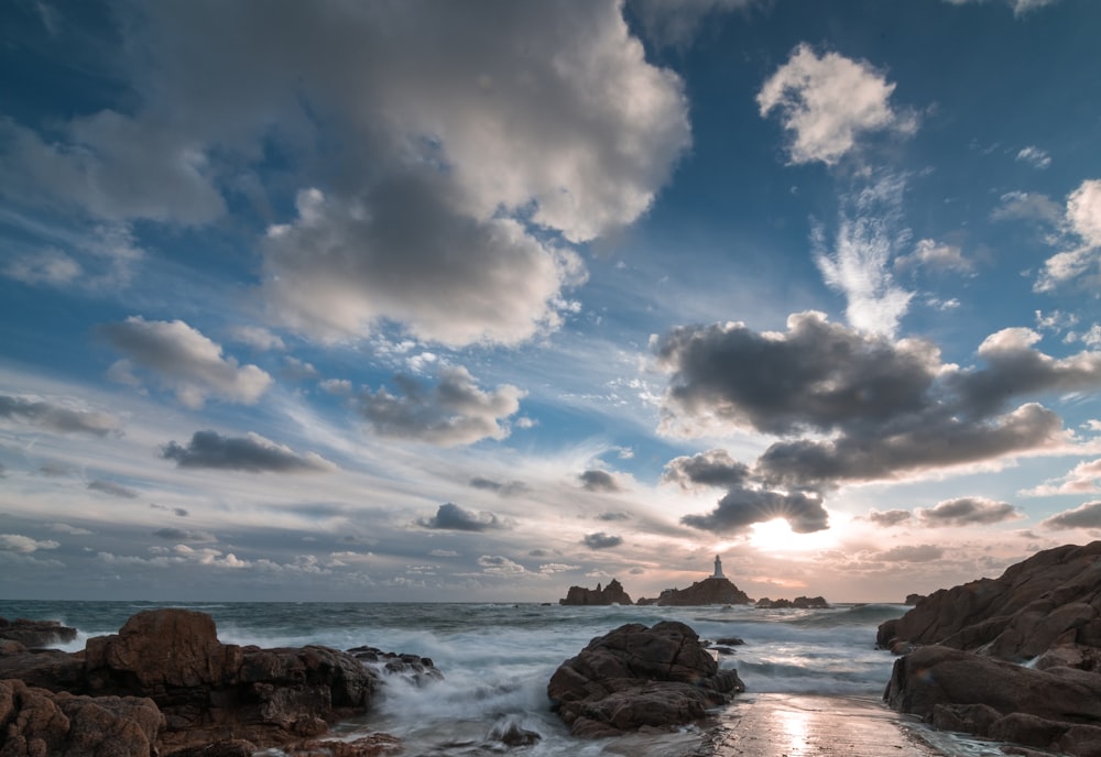 the sun is setting over a rocky beach