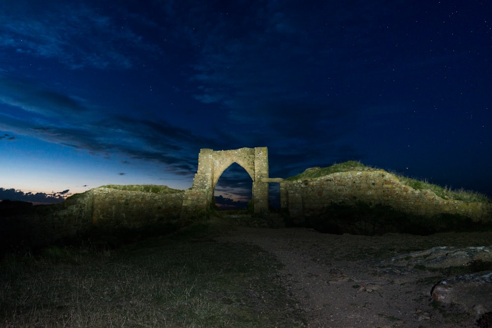 a stone structure sitting on top of a hill under a night sky