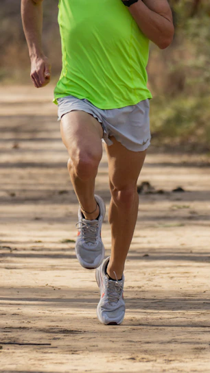 a man running down a dirt road in a green shirt