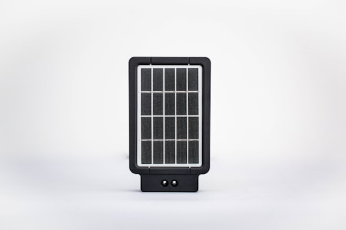 A small, rectangular solar panel device with a grid-like pattern of photovoltaic cells encased in a black frame. It is set against a clean, white background.