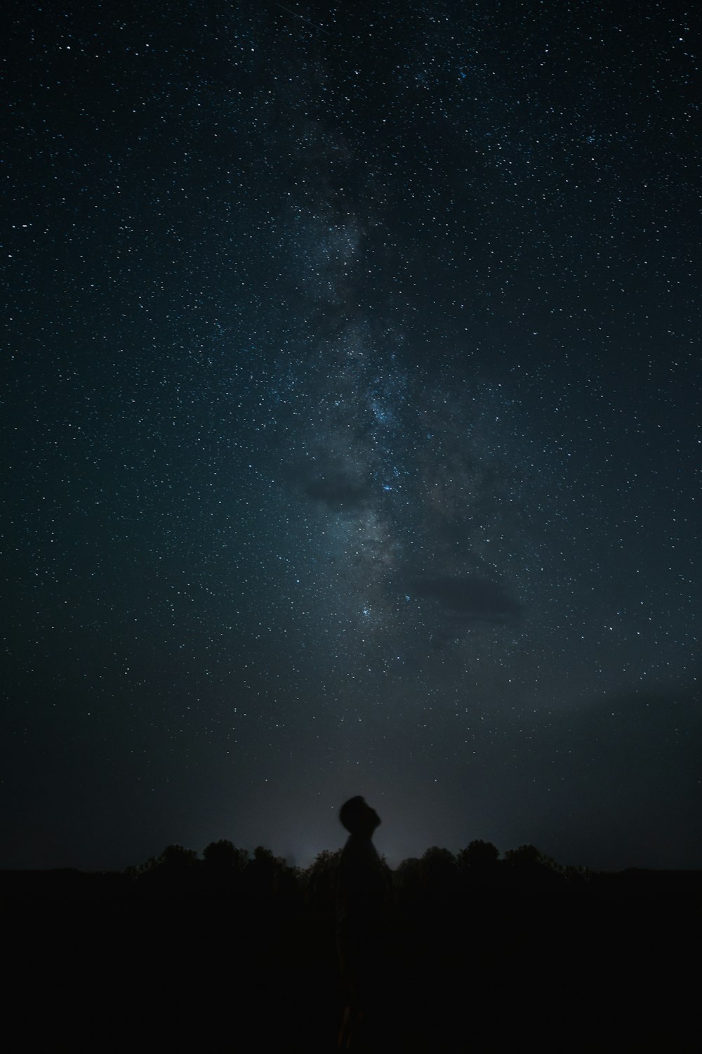 une personne debout sous un ciel nocturne avec des étoiles