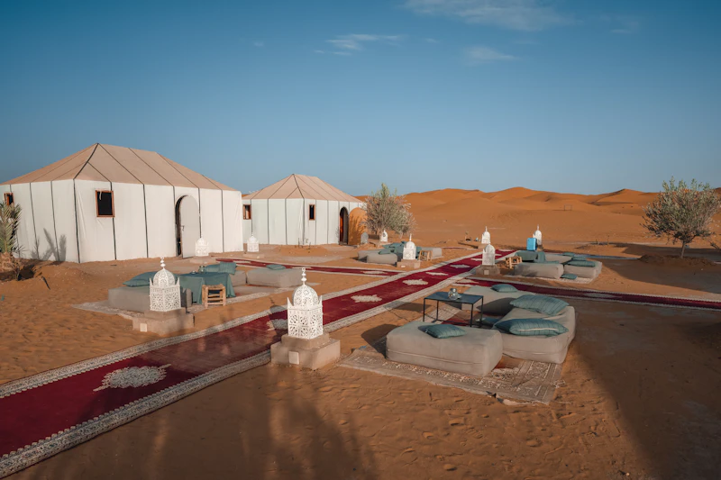 White camp tents pitched on the sand with carpets laid between them
