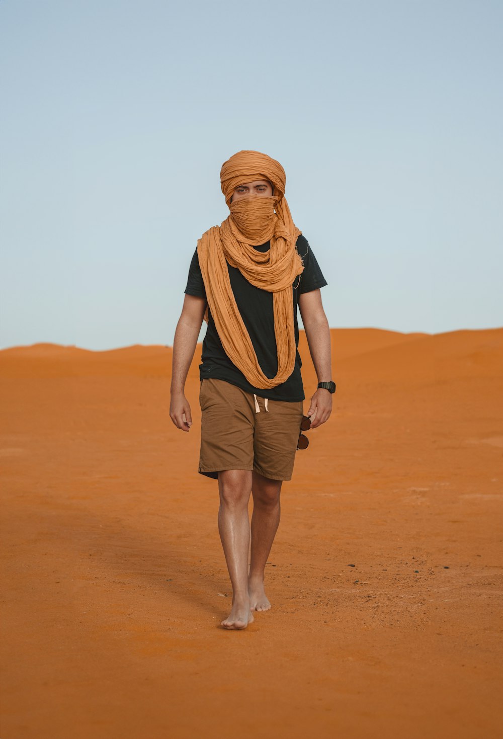 Un homme en turban marche dans le désert