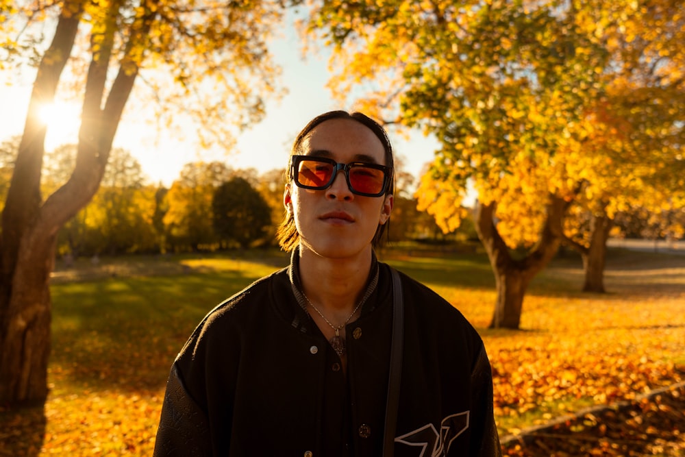 a woman wearing sunglasses standing in a park