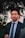 a man in a suit and tie standing in front of a tree