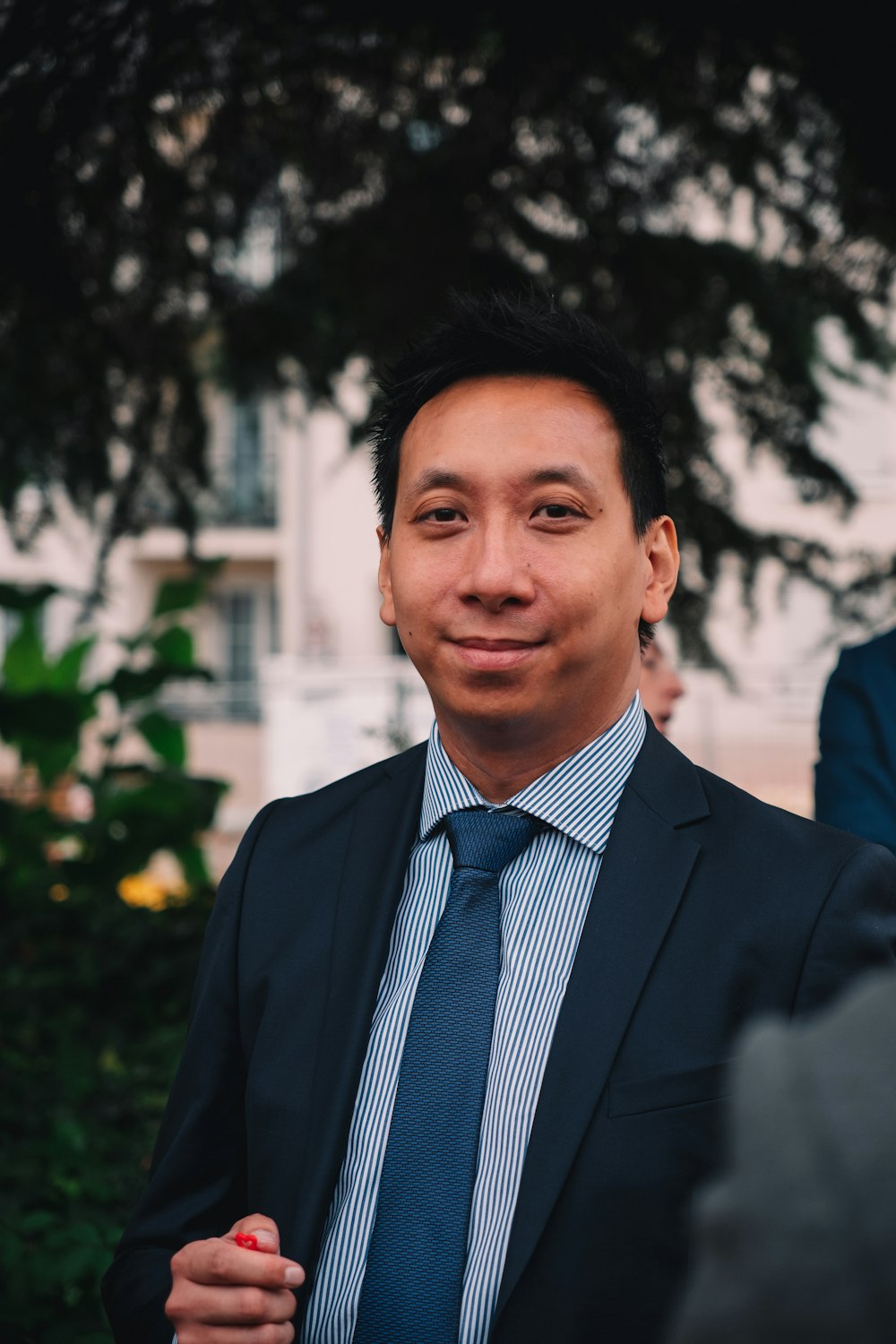 a man in a suit and tie standing in front of a tree