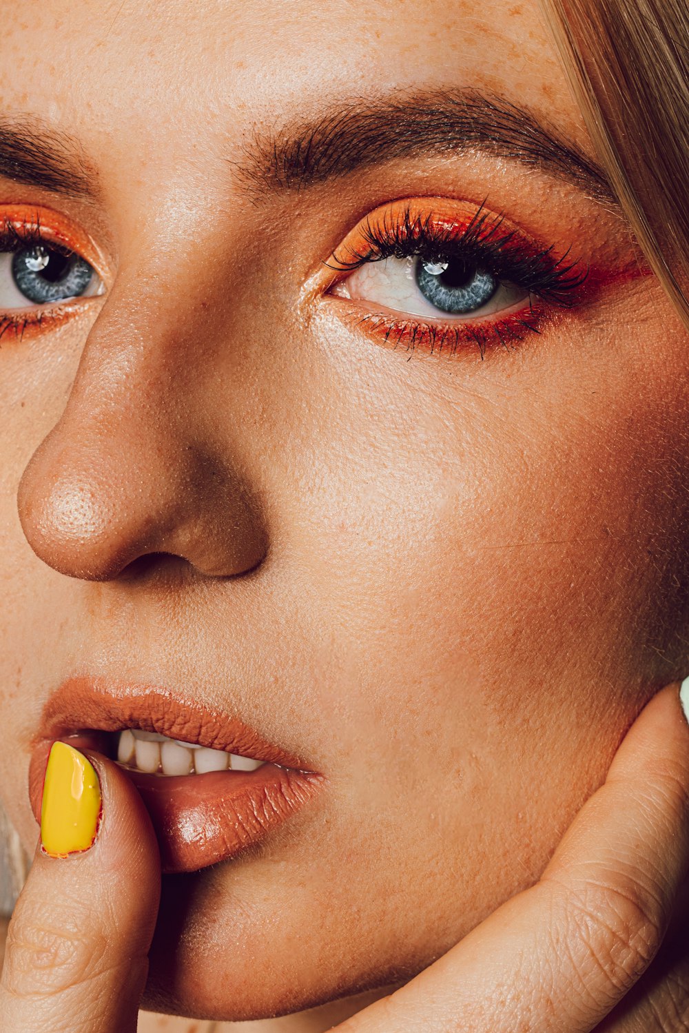 a close up of a woman with orange and yellow makeup