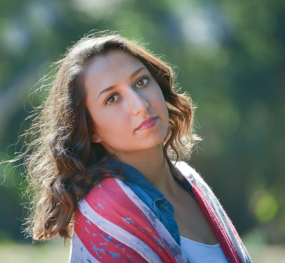 a woman in a red, white, and blue shirt looking at the camera