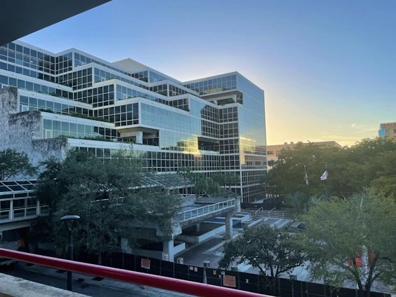 Modern office building with glass facade in a business district during sunset.