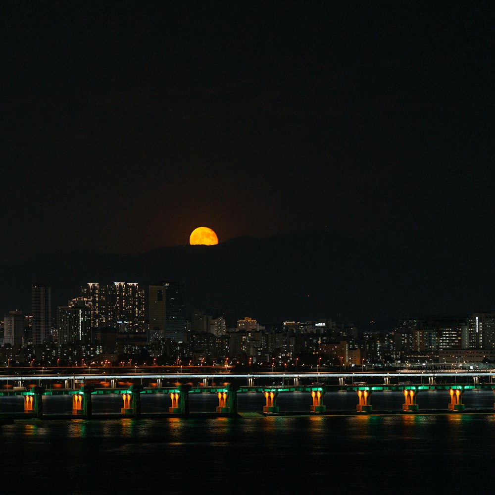 a full moon is seen over a city at night