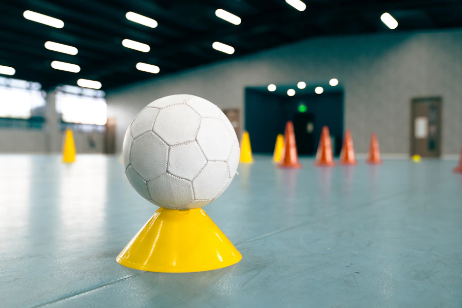 A white soccer ball resting on a yellow training cone
