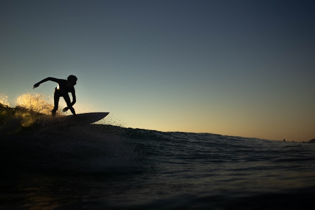 Surfer catching a wave at sunrise on Playa El Tránsito