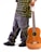 A person wearing baggy jeans and a patterned shirt stands beside a classical guitar. The guitar is leaning against their leg, and the person is holding its neck. Black sneakers complement the casual and laid-back attire.