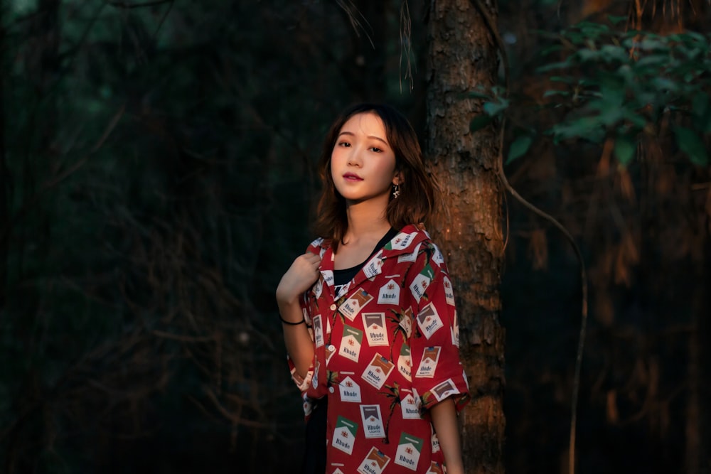 a woman standing next to a tree in a forest