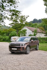 A family SUV parked on a gravel road surrounded by trees