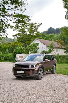 A family SUV parked on a gravel road surrounded by trees