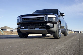 A sleek cargo truck moving through a modern industrial area under a deep blue sky.