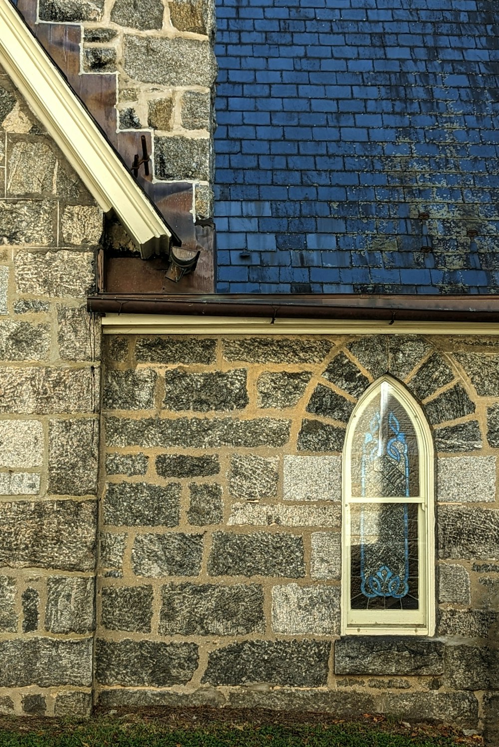 a stone building with a blue roof and a window