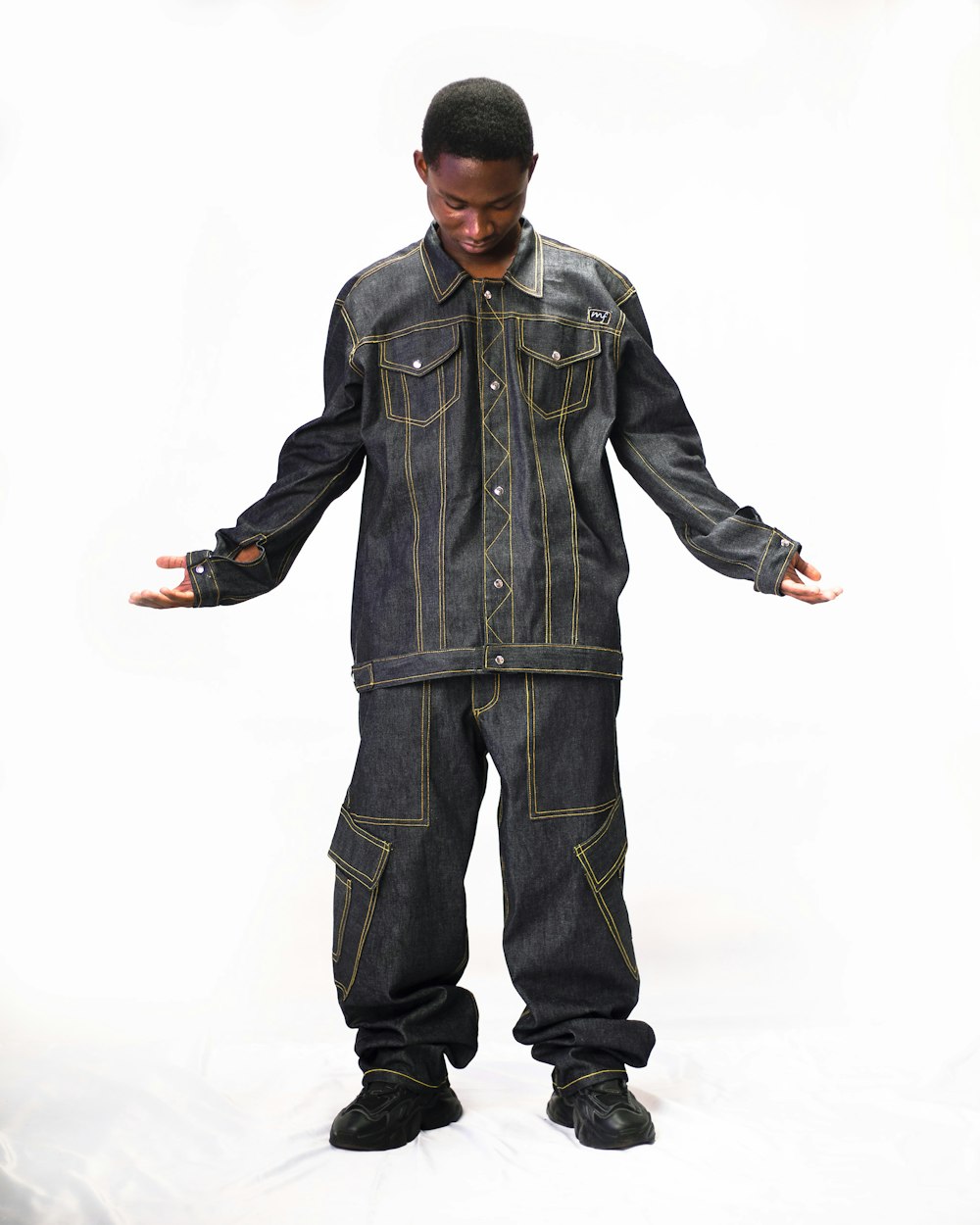 a man in a jean jumpsuit standing in front of a white background