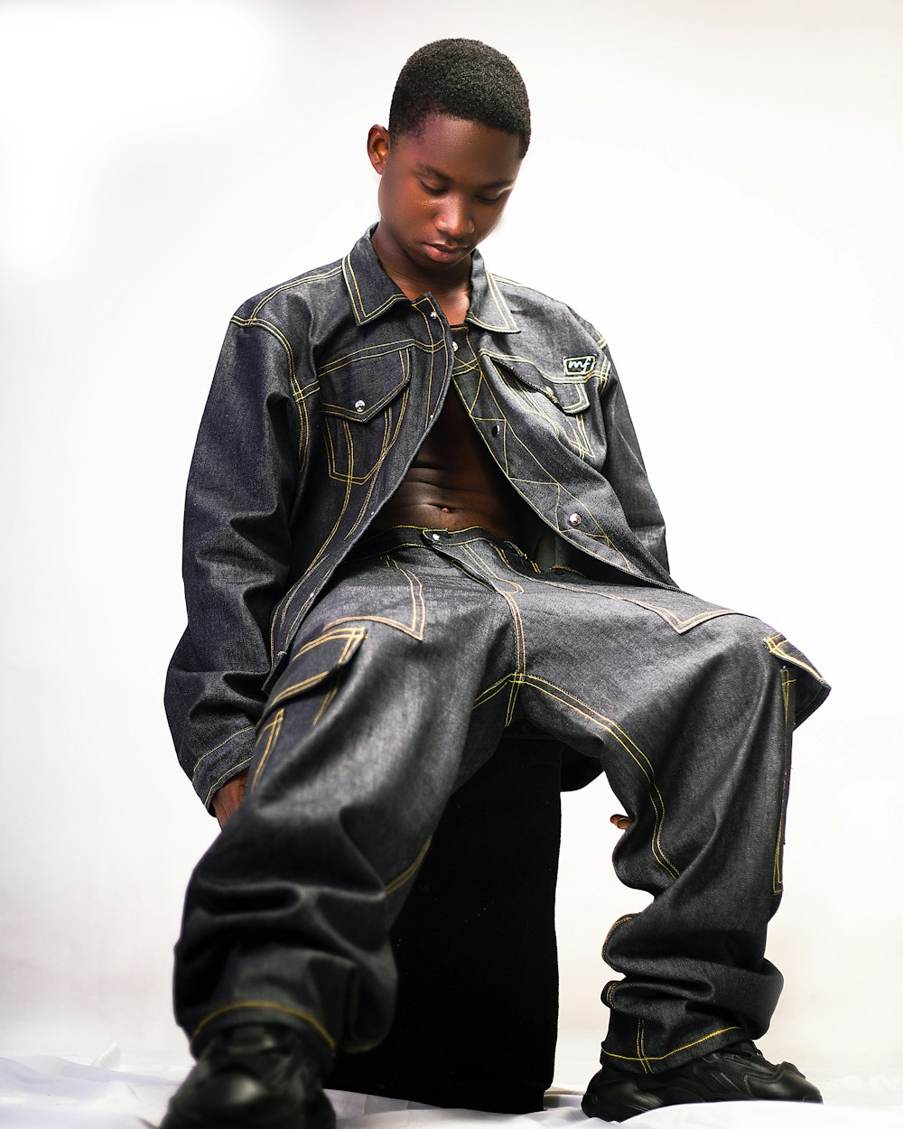 a young man sitting on top of a stool