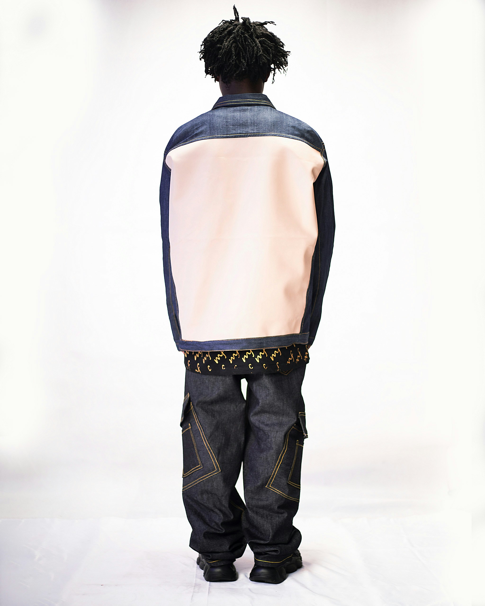 un homme avec des dreadlocks debout devant un fond blanc