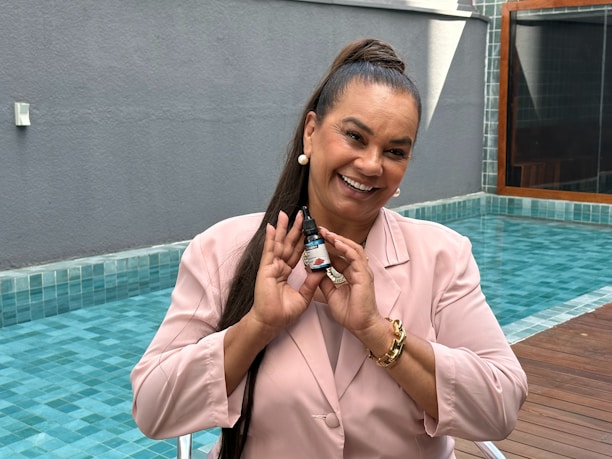 Smiling pool technician in blue uniform performing chemical balancing on a residential pool.
