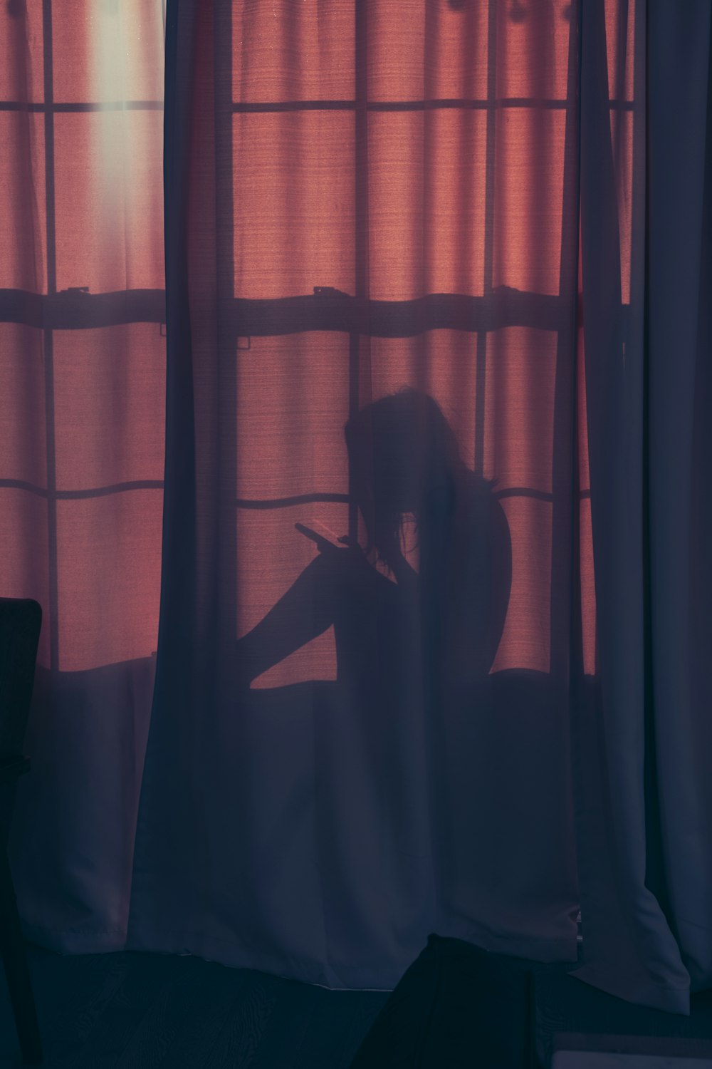 a silhouette of a woman sitting in front of a window