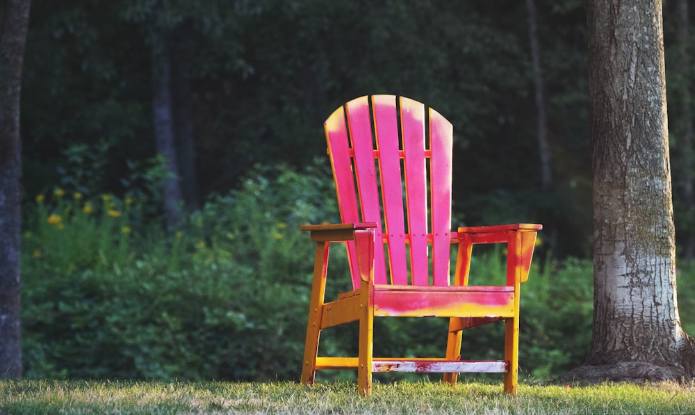 a red and yellow chair sitting next to a tree