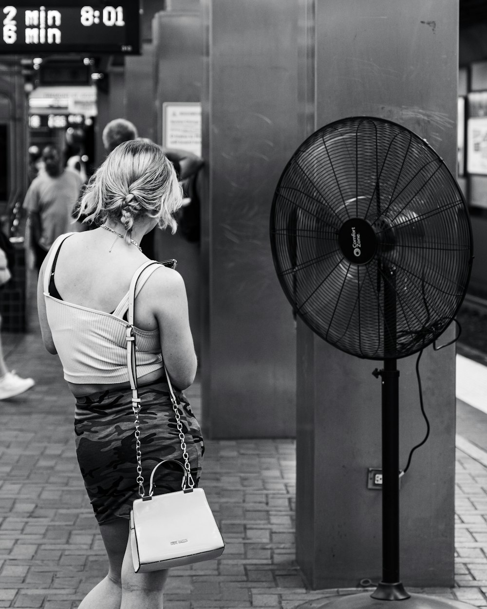 a woman in a short skirt is standing next to a fan