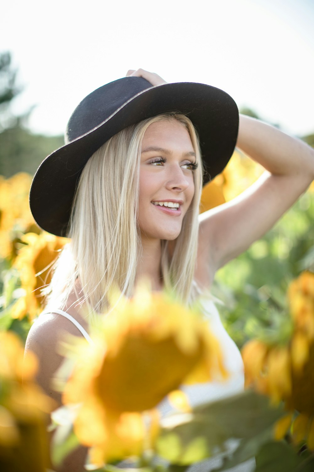 a woman wearing a hat standing in a field of sunflowers