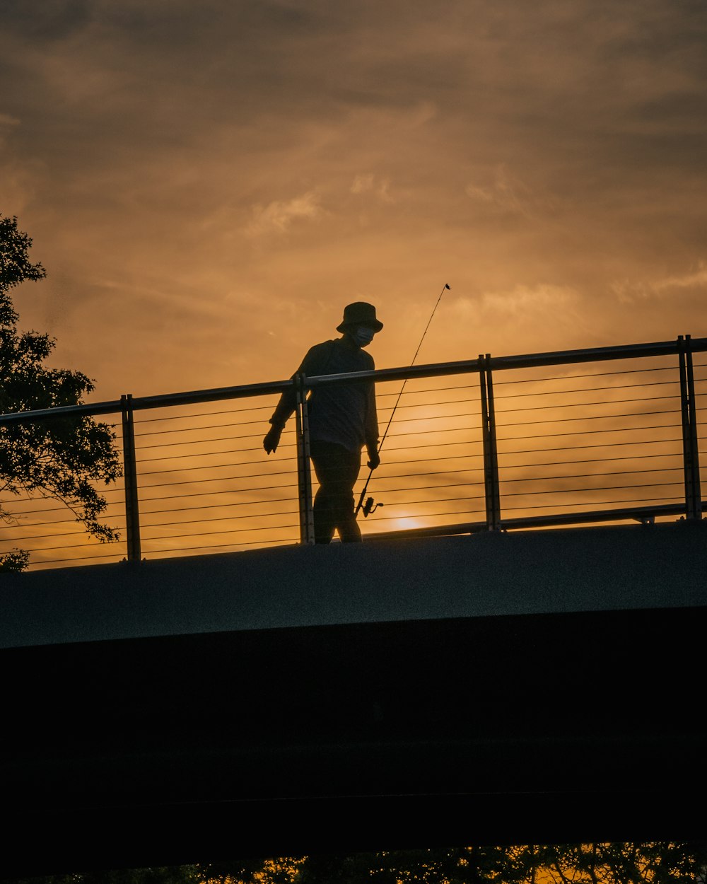 um homem caminhando através de uma ponte ao pôr do sol