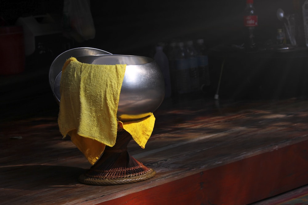 a metal bowl with a yellow towel on top of it