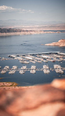 Aerial view of a coastal marina with boats docked under clear skies.