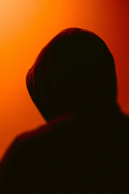 Darkly lit hoodie draped over a rusted metal surface, shadows emphasizing its textured fabric and crimson accents.