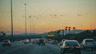 A Sonet station on a busy highway with cars charging under a bright, clear sky.