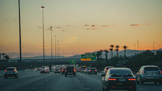 A Sonet station on a busy highway with cars charging under a bright, clear sky.