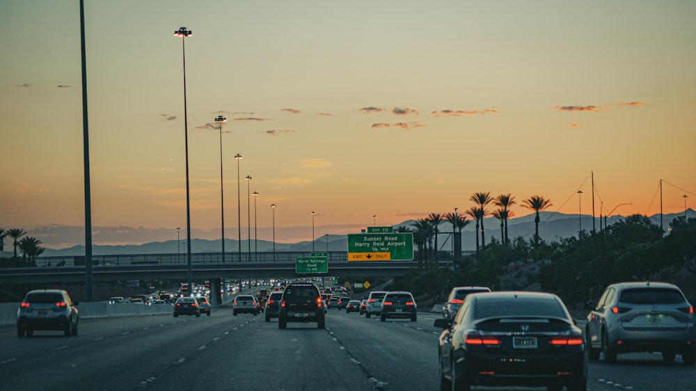 a group of cars driving down a highway at sunset