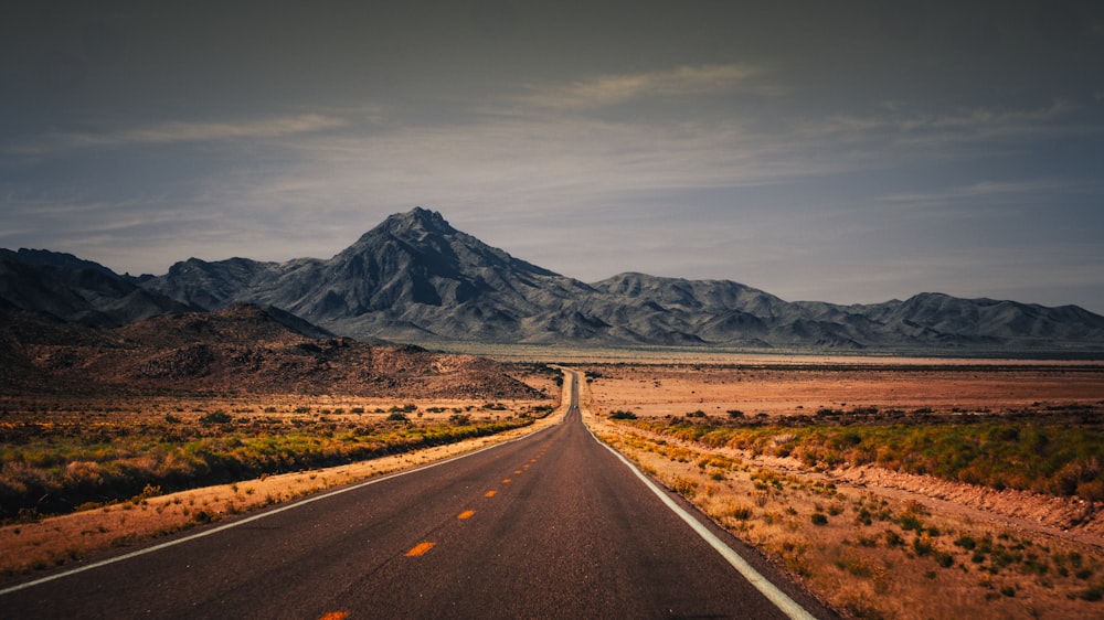 an empty road with a mountain in the background