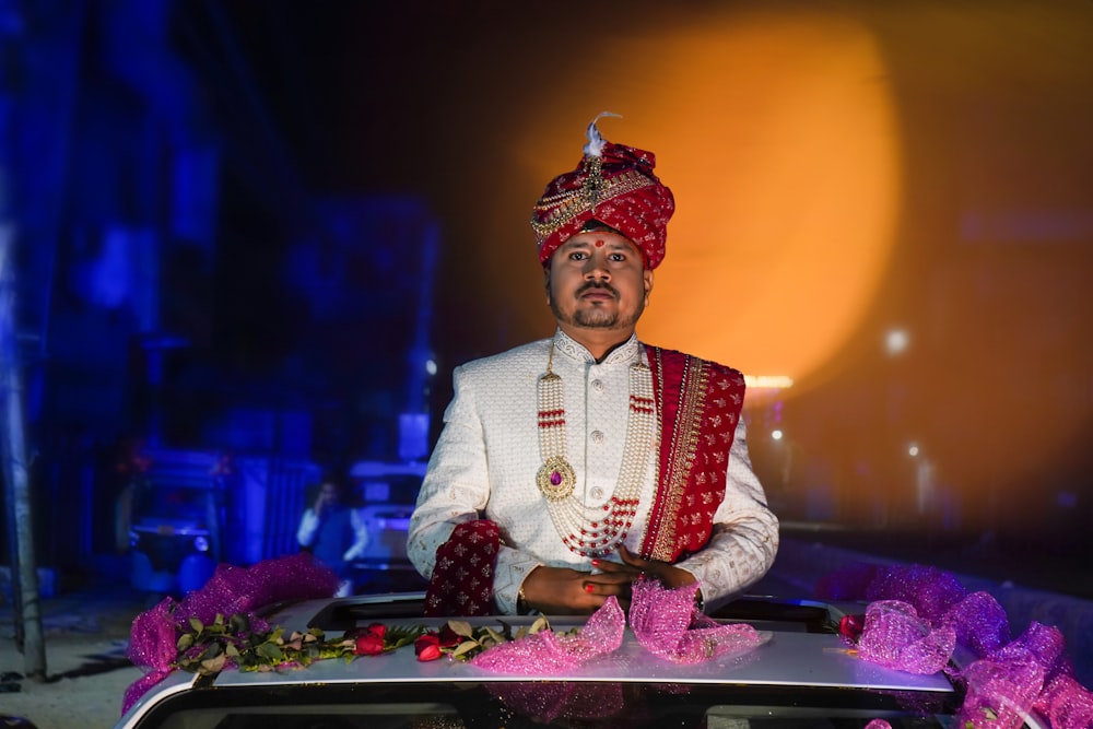 a man in a turban sitting on top of a car