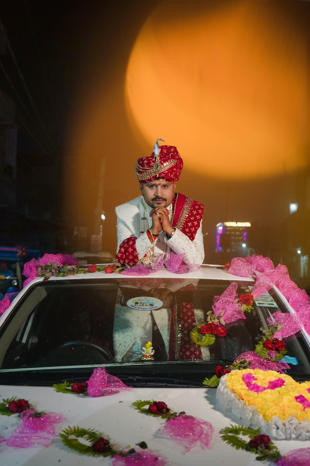 a man sitting on top of a car covered in flowers