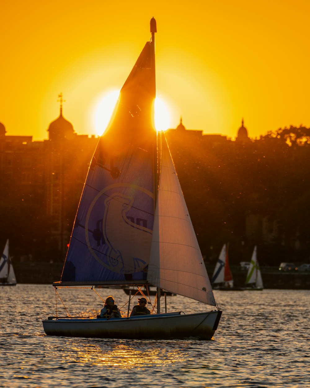 a sailboat is sailing in the water at sunset